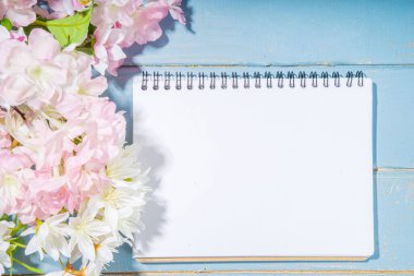 Merhaba bahar konsepti. Bahar tatili tebrik kartı suni çiçekli sade yassı arka plan açık mavi ahşap bahçe masası arkaplan çerçeve fotokopi alanı üst görünüm