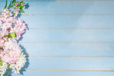 Merhaba bahar konsepti. Bahar tatili tebrik kartı suni çiçekli sade yassı arka plan açık mavi ahşap bahçe masası arkaplan çerçeve fotokopi alanı üst görünüm
