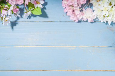 Merhaba bahar konsepti. Bahar tatili tebrik kartı suni çiçekli sade yassı arka plan açık mavi ahşap bahçe masası arkaplan çerçeve fotokopi alanı üst görünüm