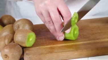 Taze kiviyi dilimleme videosu. Kadın elleri bıçakla kesilmiş taze kivi meyveleri. 