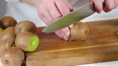 Taze kiviyi dilimleme videosu. Kadın elleri bıçakla kesilmiş taze kivi meyveleri. 