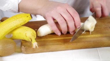 Taze muz dilimleme videosu. Kadın elleri bıçakla kesilmiş taze muz meyveleri. 
