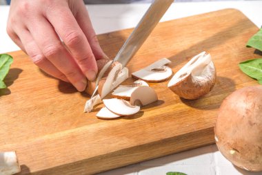 Taze mantar kesmeye yakın çekim. Kadınların elleri bıçakla kesilmiş taze mantar sebzeleri.