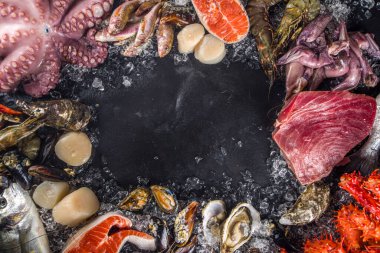 Çeşitli taze çiğ deniz ürünleri seti - ahtapot, yengeç, kalamar, karides, istiridye, midye, somon balığı limon baharatlı ton balığı, ezilmiş buzlu arka plan üst görünümü olan siyah arkaplan 