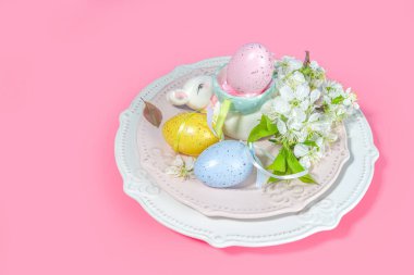 Paskalya sofrası dekorasyonu, renkli Paskalya yumurtaları, bahar bahçesi çiçekleri, tavşancık dekoru, yüksek renkli pembe arka plan fotokopi alanı.