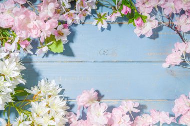 Merhaba bahar konsepti. Bahar tatili tebrik kartı suni çiçekli sade yassı arka plan açık mavi ahşap bahçe masası arkaplan çerçeve fotokopi alanı üst görünüm