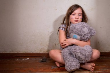 Ukrayna 'daki savaşı durdurun. Ukraynalı küçük sarışın kız, yanaklarına Ukraynalı bayraklar çizilmiş oyuncak ayılarla harap olmuş eski bir evde. Çocukları kurtar, Ukrayna 'nın gökyüzünü kapat, insani yardım felaketi konsepti
