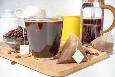 Poşetten taze demlenmiş bir fincan kahve. Süslü kahve çeşitleri, beyaz mutfak masasında fincanlar, kopyalama alanı