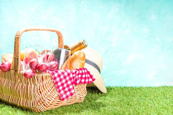 Piknik sepeti içinde yiyecek, şarap şişesi, bardaklar ve meyveler yeşil, güneşli çimlerde 