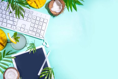 Yaz işi, serbest çalışmak, işi birleştirmek ve tatil konseptini birleştirmek. Klavye dizüstü bilgisayarı, tableti, fare, not defteri, palmiye yaprakları, tropikal meyveler ve kokteyl, afiş başlığı üst görünümü
