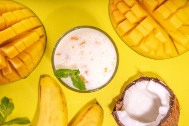 Yoğurt, milkshake ya da meyve suyu. Meyveli milkshake ile üç bardak. Beyaz muz, yeşil elma avokadosu, sarı mango tropikal meyve püresi. Parlak sarı masaya, boşluğu kopyala