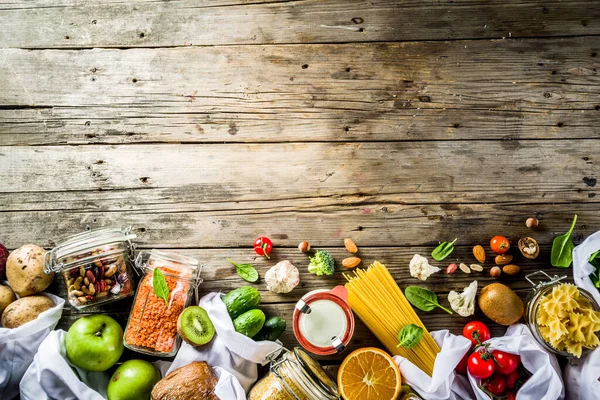 Sıfır atık alışverişi ve sürdürülebilir yaşam tarzı konsepti, çeşitli çiftlik organik sebzeleri, tahıllar, makarna, yumurta ve meyveler yeniden kullanılabilir paketleme poşetlerinde. Boşluk üst görünümünü kopyala