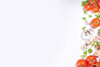 Yemek hazırlama geçmişi. Mutfak masası arka planında baharatlar, otlar, sebzeler. Maydanoz, soğan, sarımsak, domates, tuz, zeytinyağı beyaz arka planda düz görünüm fotokopi alanı