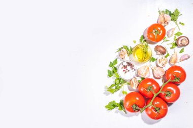 Yemek hazırlama geçmişi. Mutfak masası arka planında baharatlar, otlar, sebzeler. Maydanoz, soğan, sarımsak, domates, tuz, zeytinyağı beyaz arka planda düz görünüm fotokopi alanı