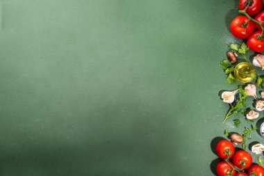 Yemek hazırlama geçmişi. Mutfak masası arka planında baharatlar, otlar, sebzeler. Maydanoz, soğan, sarımsak, domates, tuz, zeytinyağı koyu yeşil arka planda düz görünüm fotokopi alanı