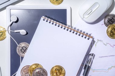 Ofis masaüstü çalışma alanındaki bitcoin paralar. Kripto para piyasası konseptiyle çalışmak. Klavye, dizüstü bilgisayar, tablet, fare, büyüyen bitcoin oranının grafikleri beyaz ofis masasında, üst görünüm kopyalama alanı