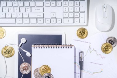 Ofis masaüstü çalışma alanındaki bitcoin paralar. Kripto para piyasası konseptiyle çalışmak. Klavye, dizüstü bilgisayar, tablet, fare, büyüyen bitcoin oranının grafikleri beyaz ofis masasında, üst görünüm kopyalama alanı