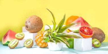 Yaz kompozisyonu, çeşitli tropikal meyveler, modern, parlak sarı arka planda podyumlar, kopyalama alanı. Tatil ve tatil, sağlıklı gıda konsepti boşluğu kopyalamak