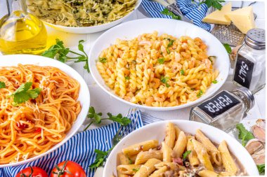 Beyaz fayanslı arka planda farklı soslu makarna seti. Spagetti, farfalle, makarna, deniz ürünleri, ıspanak, karbonara, domates soslu fusilli makarna. İtalyan yemeği, Akdeniz yemeği konsepti