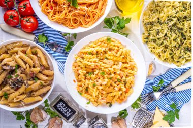 Beyaz fayanslı arka planda farklı soslu makarna seti. Spagetti, farfalle, makarna, deniz ürünleri, ıspanak, karbonara, domates soslu fusilli makarna. İtalyan yemeği, Akdeniz yemeği konsepti