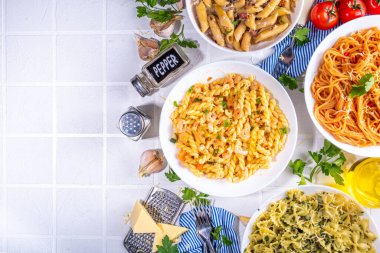Beyaz fayanslı arka planda farklı soslu makarna seti. Spagetti, farfalle, makarna, deniz ürünleri, ıspanak, karbonara, domates soslu fusilli makarna. İtalyan yemeği, Akdeniz yemeği konsepti