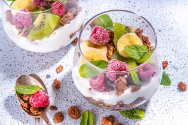 Yaz sağlıklı diyet kahvaltısı, atıştırmalık konsepti. Yoğurt, taze böğürtlen ve meyveli üç katlı granola kahvaltılık tatlı. İki porsiyonlu bardak ve bir gecede yulaf ezmesi parfümlü tatlı.