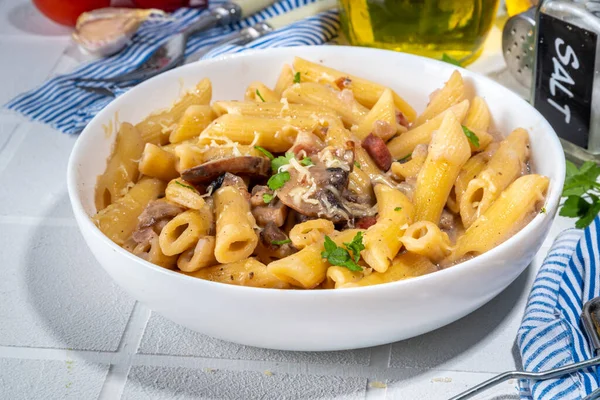 İtalyan Akdeniz yemek konsepti. Kremalı Carbonara mantar soslu makarna. Akşam yemeği için baharatlarla dolu beyaz bir fayans masasında. 