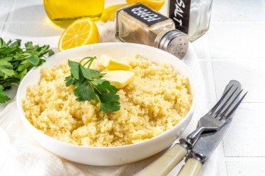 Kişniş ya da maydanozlu kuskus, tereyağı, zeytin yağı, beyaz seramik kasede limon, mutfak masasında beyaz fotokopi alanı.
