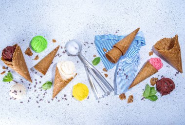 Waffle külahlarında parlak renkli dondurma koleksiyonu, beyaz beton arka planda çeşitli aromalı dondurma seti