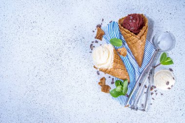 Vanilla and chocolate ice cream on white background. Classic summer gelato taste in waffle cones, with ice cream scoop, chocolate and sugar sprinkles, summer dessert flavor concept, top view copy space