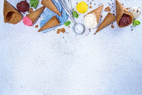 Waffle külahlarında parlak renkli dondurma koleksiyonu, beyaz beton arka planda çeşitli aromalı dondurma seti