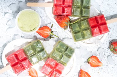 Sütsüz yeşil kibrit ve çilekli dondurma. Yeşil kibrit çay tozu ve dut suyu ile vejetaryen dondurması, beyaz beton arka planda sağlıklı organik tatlı.