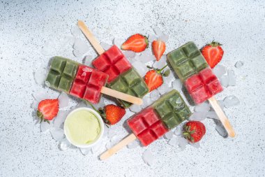 Sütsüz yeşil kibrit ve çilekli dondurma. Yeşil kibrit çay tozu ve dut suyu ile vejetaryen dondurması, beyaz beton arka planda sağlıklı organik tatlı.