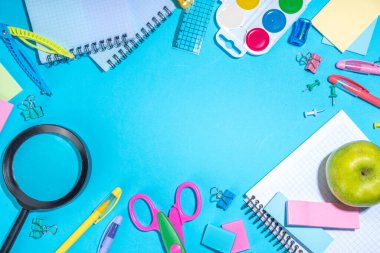 Düz bir zemin, parlak mavi arka planda renkli eğitim malzemeleri vardı. Okul konseptine geri dönelim. Okul çantasında makas, not defteri, kalem, kalem ve malzeme var. Üst görünüm, üstten kopyalama alanı