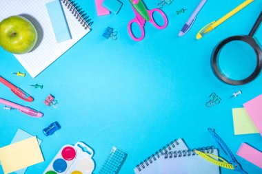 Düz bir zemin, parlak mavi arka planda renkli eğitim malzemeleri vardı. Okul konseptine geri dönelim. Okul çantasında makas, not defteri, kalem, kalem ve malzeme var. Üst görünüm, üstten kopyalama alanı