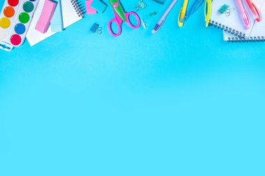 Düz bir zemin, parlak mavi arka planda renkli eğitim malzemeleri vardı. Okul konseptine geri dönelim. Okul çantasında makas, not defteri, kalem, kalem ve malzeme var. Üst görünüm, üstten kopyalama alanı