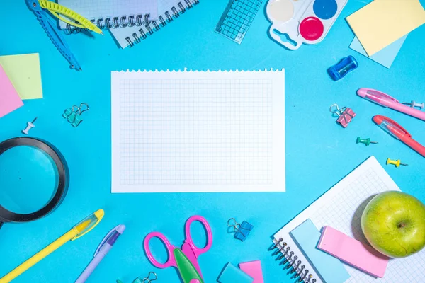 Flat lay background with colorful educational  supplies on bright blue background. Back to school concept. School backpack with scissors, notepads, pen, pencils, supply. Top view, overhead copy space