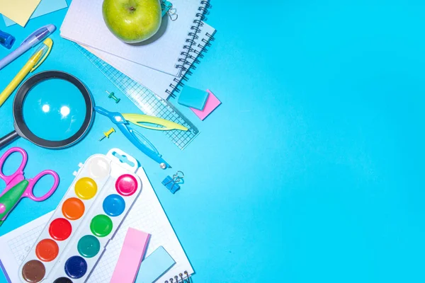 Düz bir zemin, parlak mavi arka planda renkli eğitim malzemeleri vardı. Okul konseptine geri dönelim. Okul çantasında makas, not defteri, kalem, kalem ve malzeme var. Üst görünüm, üstten kopyalama alanı