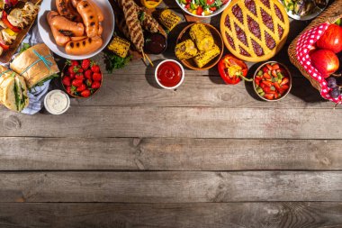 Çeşitli piknik barbekü yemekleri ve flatlay içiyorlar. Yaz bbq piknik yemekleri, ızgara etler, kebaplar, sebzeler, meyve salatası, geleneksel piknik pastası, sandviçler, üst görünüm fotokopi alanı.