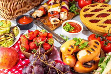 Çeşitli piknik barbekü yemekleri ve flatlay içiyorlar. Yaz bbq piknik yemekleri, ızgara etler, kebaplar, sebzeler, meyve salatası, geleneksel piknik pastası, sandviçler, üst görünüm fotokopi alanı.