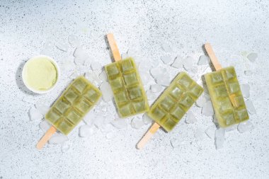 Vejetaryen kiraz yeşil buzlu çay. Vejetaryen diyeti hindistancevizi matcha latte dondurma lolipopları beyaz masa arkasında 