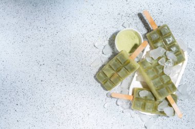 Vejetaryen kiraz yeşil buzlu çay. Vejetaryen diyeti hindistancevizi matcha latte dondurma lolipopları beyaz masa arkasında 