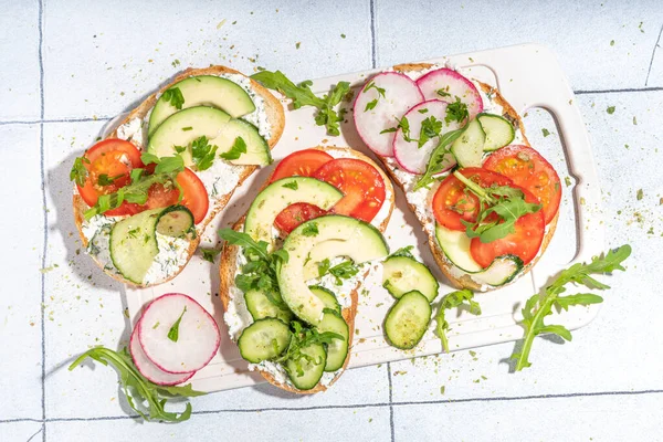 Krem peynirli tost veya süzme peynirli, taze sebzeli - domates, avokado, turp, salatalık, sağlıklı diyet bahar sandviçi, İskandinav tostları üst görünüm fotokopi alanı