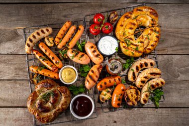 Bavyera sosisi, yuvarlak, gumberland, ketçaplı sucuk, hardal barbekü sosu. Çeşitli bbq ızgara sosisler ahşap arka planda yatıyordu. Sokak festivali ızgara yemek menüsü. 