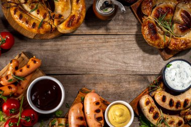 Bavyera sosisi, yuvarlak, gumberland, ketçaplı sucuk, hardal barbekü sosu. Çeşitli bbq ızgara sosisler ahşap arka planda yatıyordu. Sokak festivali ızgara yemek menüsü. 