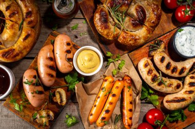 Bavyera sosisi, yuvarlak, gumberland, ketçaplı sucuk, hardal barbekü sosu. Çeşitli bbq ızgara sosisler ahşap arka planda yatıyordu. Sokak festivali ızgara yemek menüsü. 
