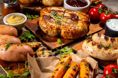 Bavyera sosisi, yuvarlak, gumberland, ketçaplı sucuk, hardal barbekü sosu. Çeşitli bbq ızgara sosisler ahşap arka planda yatıyordu. Sokak festivali ızgara yemek menüsü. 