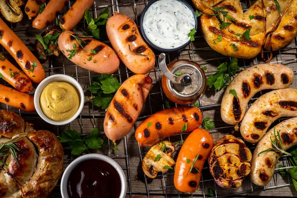 Bavyera sosisi, yuvarlak, gumberland, ketçaplı sucuk, hardal barbekü sosu. Çeşitli bbq ızgara sosisler ahşap arka planda yatıyordu. Sokak festivali ızgara yemek menüsü. 