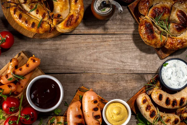 Bavyera sosisi, yuvarlak, gumberland, ketçaplı sucuk, hardal barbekü sosu. Çeşitli bbq ızgara sosisler ahşap arka planda yatıyordu. Sokak festivali ızgara yemek menüsü. 