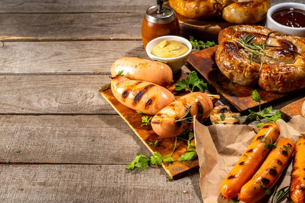 Bavyera sosisi, yuvarlak, gumberland, ketçaplı sucuk, hardal barbekü sosu. Çeşitli bbq ızgara sosisler ahşap arka planda yatıyordu. Sokak festivali ızgara yemek menüsü. 
